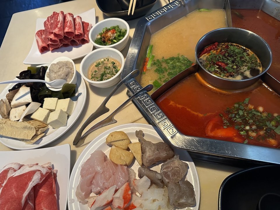 Fresh vegetables arranged beside broth pots